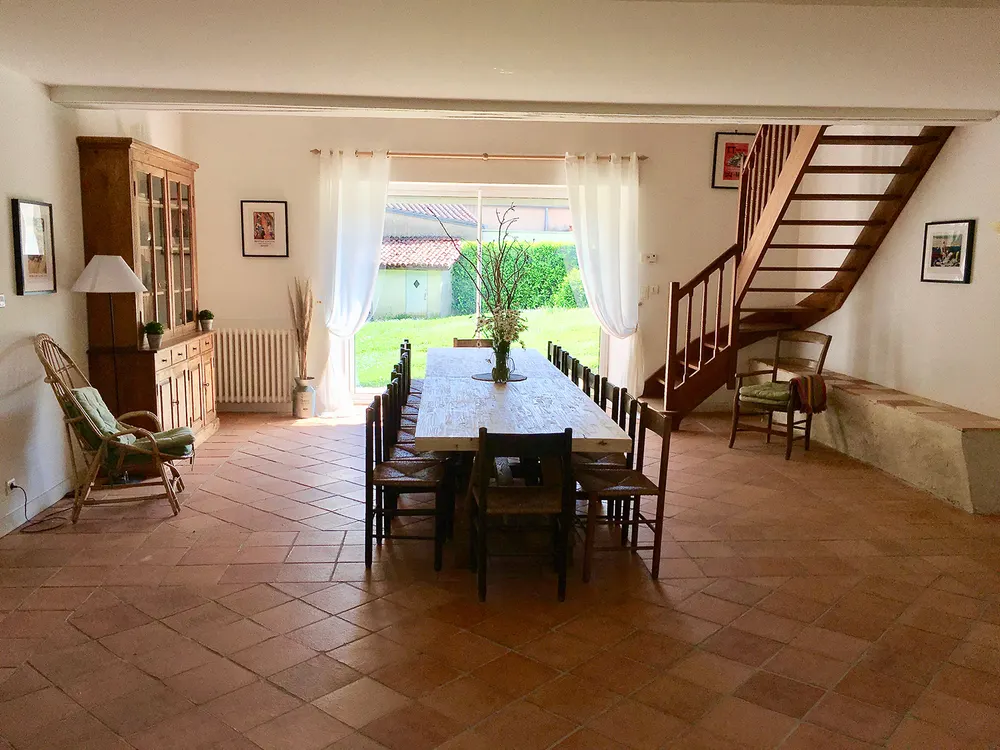 Grande salle à manger d'un gîte, avec son escalier en bois